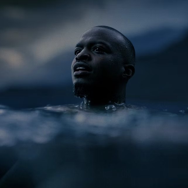 A man surfacing from dark water