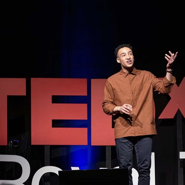 Luke on stage in front of the TEDx letters